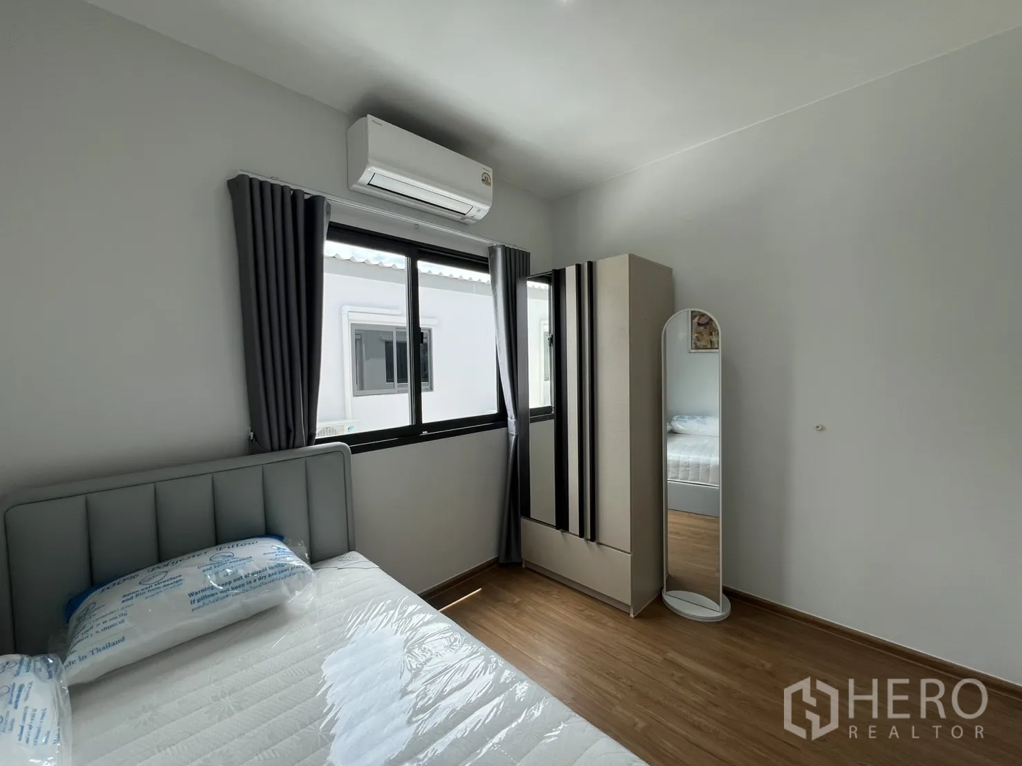 Townhouse for rent in Bang Phli, Samut Prakan - Secondary bedroom with bed, air conditioner, wardrobe and mirror.