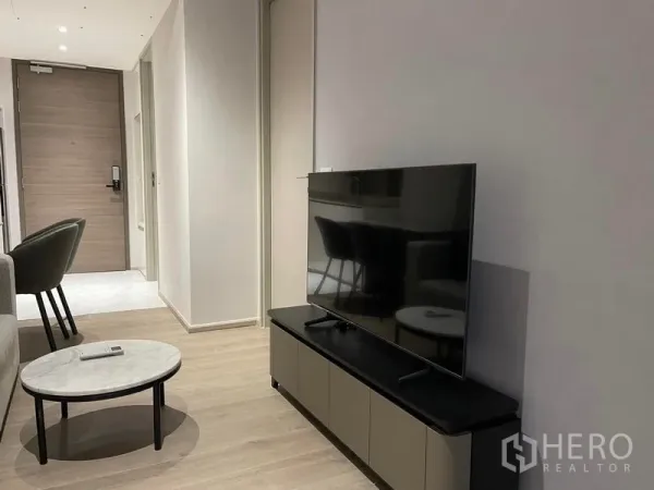 คอนโด ให้เช่าในKhlong Toei, Bangkok - ห้องนั่งเล่นมินิมอลมีชั้นวางทีวี โต๊ะกลม พื้นไม้โทนอ่อน