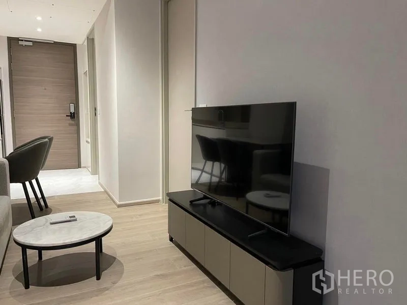 คอนโด ให้เช่าในKhlong Toei, Bangkok - ห้องนั่งเล่นมินิมอลมีชั้นวางทีวี โต๊ะกลม พื้นไม้โทนอ่อน