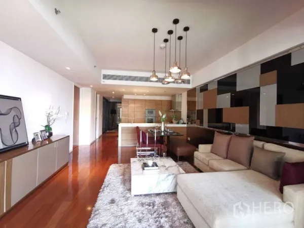 Condominium for rent in Yan Nawa, Bangkok - Open-plan living and dining area with sectional sofa, marble coffee table, pendant lights and modern kitchen.