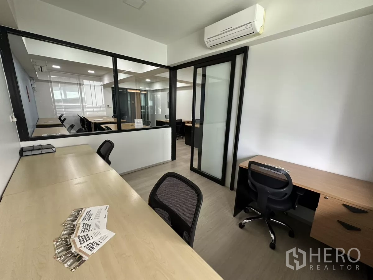 Office Space for rent in Watthana, Bangkok - Glass-partitioned room with desks on both sides, a sliding door and a split-type air conditioner.