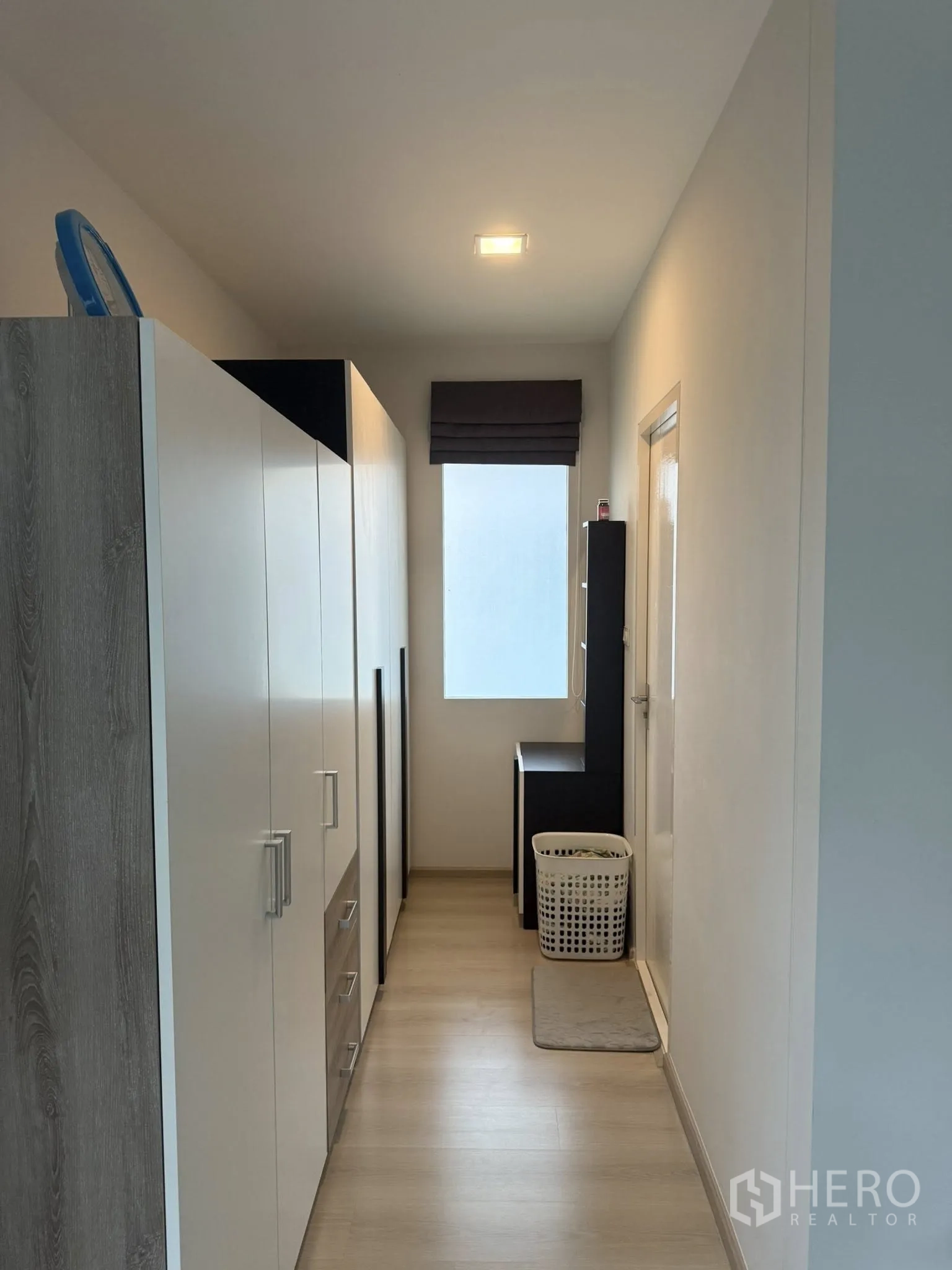 Townhouse for rent or sale in Sai Mai, Bangkok - Upper hallway lined with wardrobes and a window bringing in natural light.
