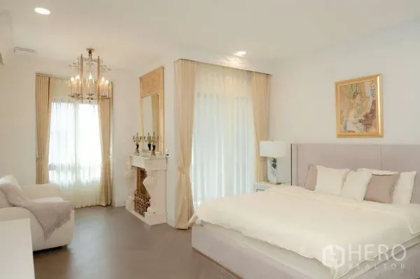 บ้าน ให้เช่าหรือขายในSaphan Sung, Bangkok - ห้องนอนมาสเตอร์สว่างไสว โคมไฟระย้า เตาผิงตกแต่ง หน้าต่างบานใหญ่ และเตียงบุผ้า