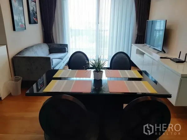 คอนโด ให้เช่าในWatthana, Bangkok - ห้องนั่งเล่นและรับประทานอาหารสว่าง พร้อมโต๊ะกระจก ตู้ทีวี และประตูระเบียงหลังผ้าม่านโปร่ง