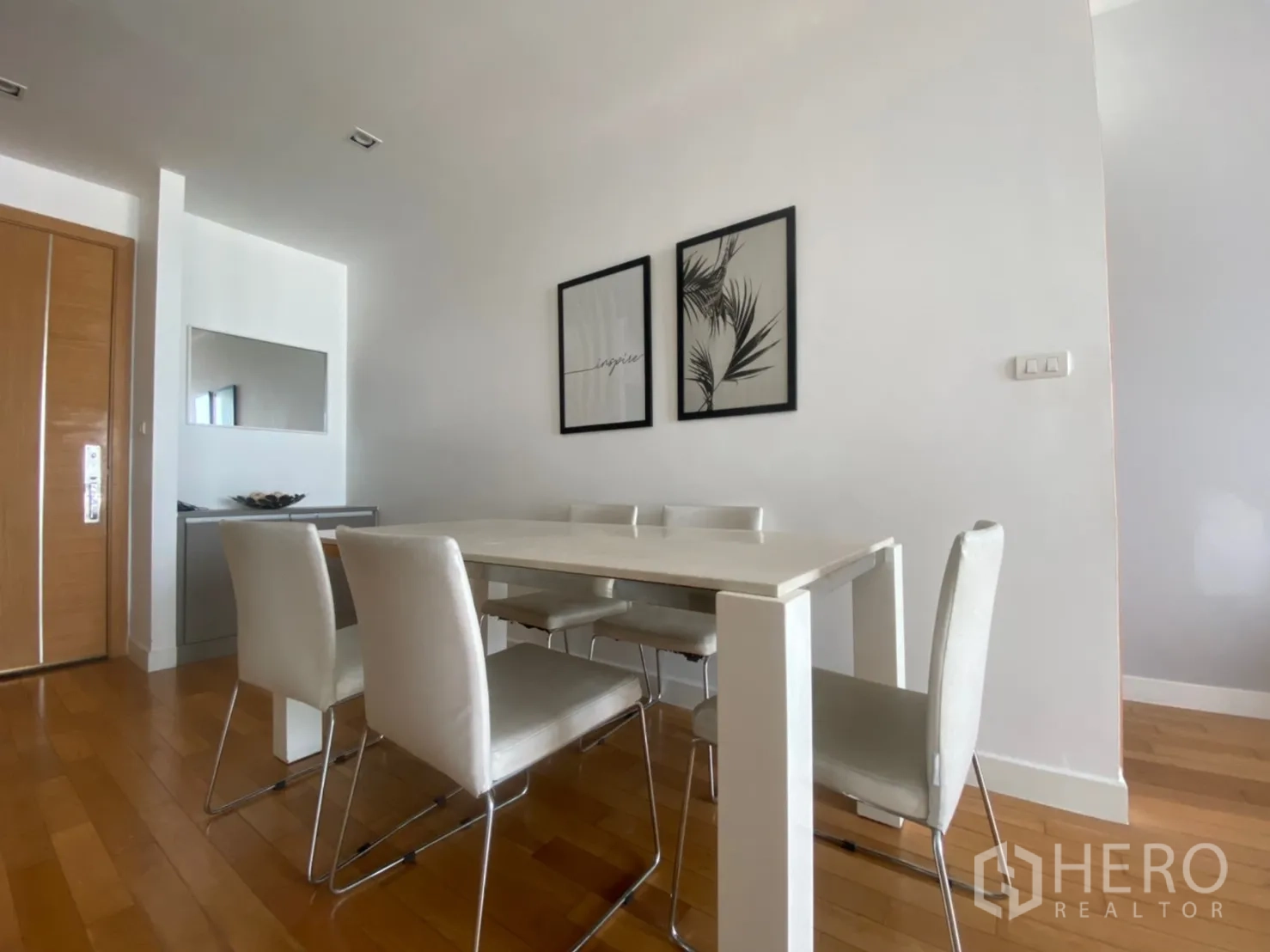 คอนโด ให้เช่าหรือขายในKhlong Toei, Bangkok - มุมรับประทานอาหารมินิมอล โต๊ะและเก้าอี้สีขาว ข้างประตูไม้และกรอบรูปผนัง