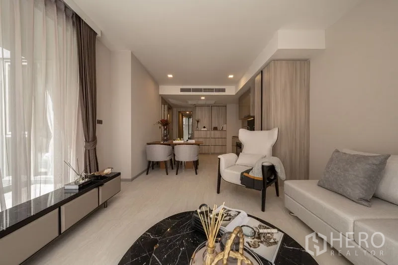 คอนโด ให้เช่าในWatthana, Bangkok - มุมมองจากห้องนั่งเล่นไปยังส่วนรับประทานอาหารและครัว พร้อมเก้าอี้อาร์มแชร์