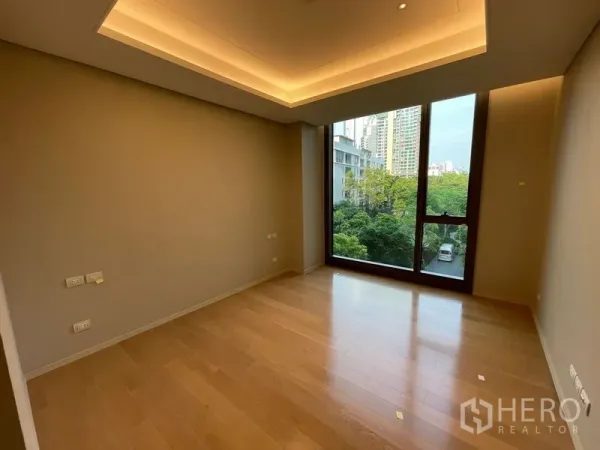 Condominium for rent or sale in Pathum Wan, Bangkok - Bright bedroom with floor-to-ceiling window, recessed ceiling lights and wood floors overlooking green views in Lumphini, Pathum Wan.