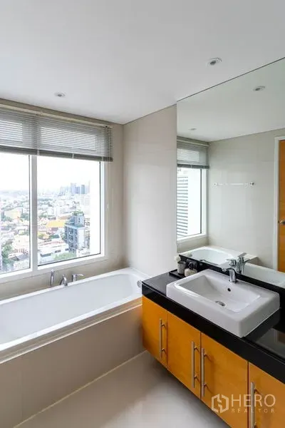 公寓 出租在Watthana, Bangkok - 浴室配靠窗浴缸，超大窗户观景，台上盆与大镜子。