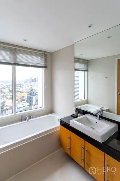 公寓 出租在Watthana, Bangkok - 浴室配靠窗浴缸，超大窗户观景，台上盆与大镜子。