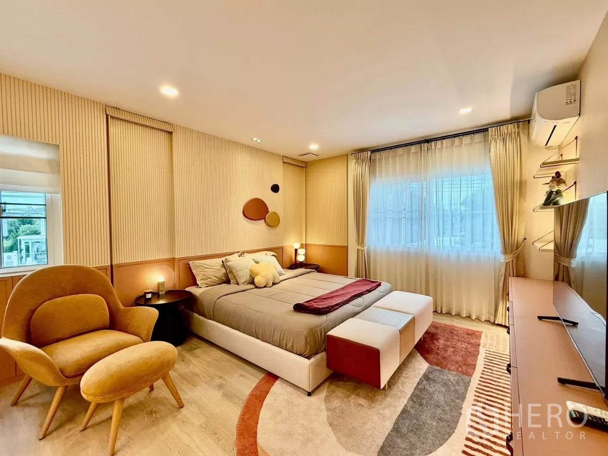 Detached House for rent in Bang Phli, Samut Prakan - Primary bedroom with accent wall, armchair and large windows.