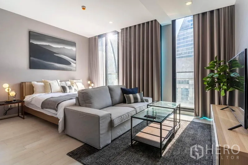 คอนโด ให้เช่าในPathum Wan, Bangkok - เลย์เอาต์สไตล์สตูดิโอรวมเตียง โซฟา ชุดทีวี และผนังกระจกพร้อมผ้าม่าน