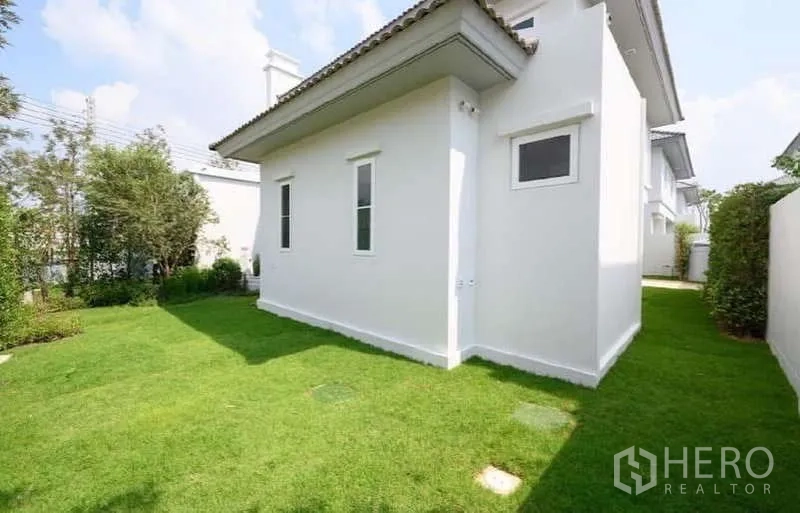 Detached House for rent or sale in Bang Phli, Samut Prakan - Rear corner lawn surrounding the white exterior walls of the home.