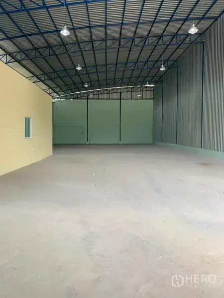 工厂 出租在Khlong Luang, Pathum Thani - 宽阔厂房空间，高钢桁架屋顶与高棚灯，后方配卷闸门