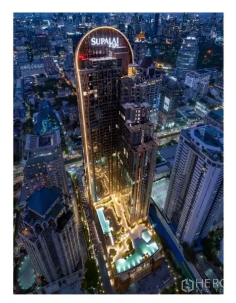 公寓 出租在Sathon, Bangkok - 夜景航拍，高层公寓大楼在沙吞天际线中灯火通明。