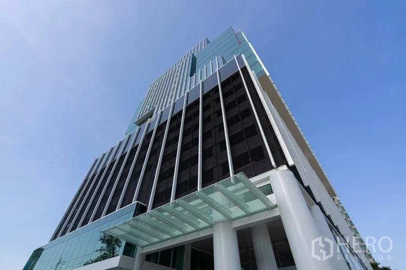 Office Space for rent in Bang Rak, Bangkok - Modern glass-and-steel office tower exterior shot from below against a blue sky.