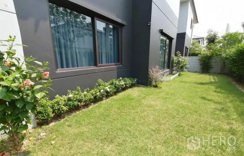 Detached House for sale in Bang Phli, Samut Prakan - Side garden with green lawn, shrubs and large house windows in Bang Phli.