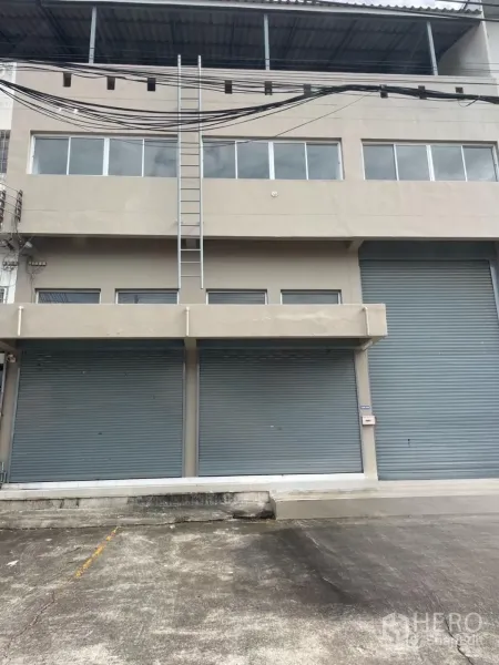货栈 出租在Bang Phli, Samut Prakan - 北榄府邦普里仓库外立面，临街多卷闸门、装卸前场与顶部遮棚