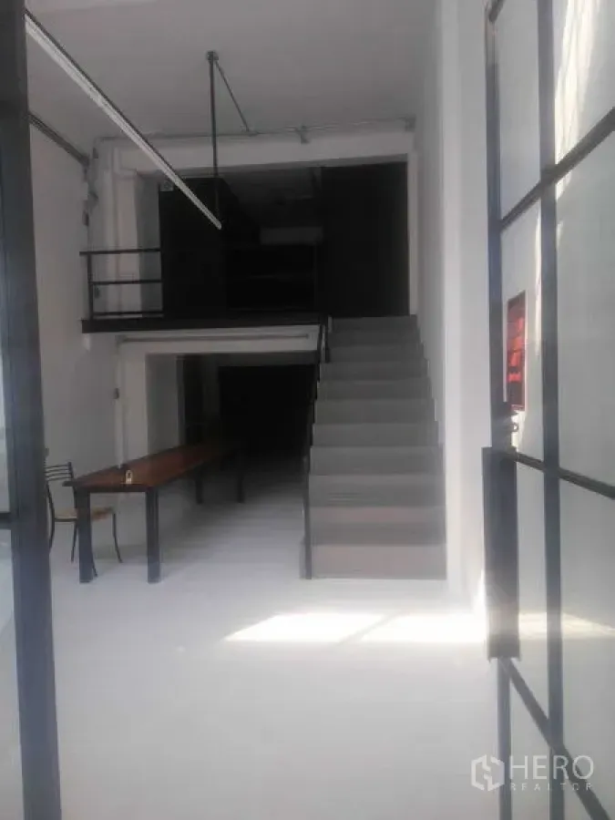 Shophouse for rent in Khlong Toei, Bangkok - Front retail space viewed from the entrance, showing staircase and mezzanine.