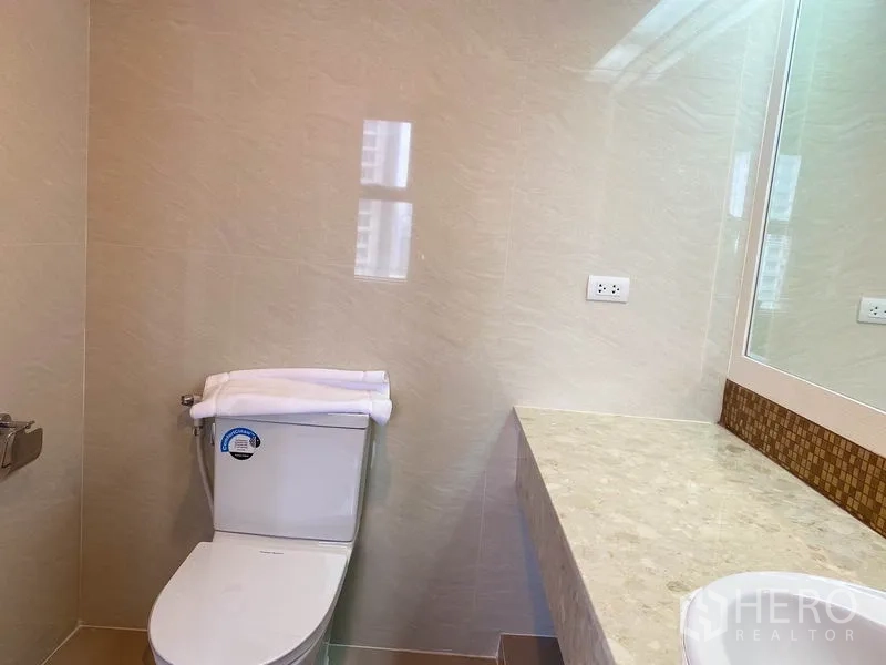 公寓 出租在Watthana, Bangkok - 客卫，坐便器、长石质台面与大镜子。