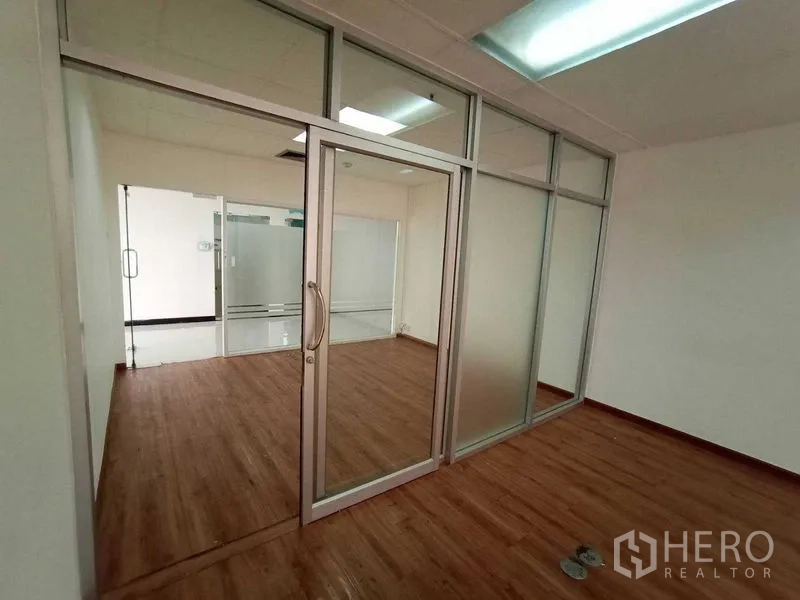 Office Space for rent - Bright office room with glass partitions and wood flooring.