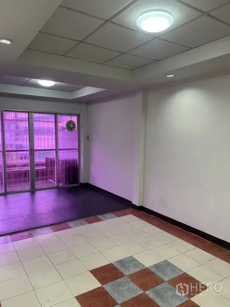 Townhouse for rent in Khlong Toei, Bangkok - Open-plan room leading to sliding glass doors and a small balcony with purple tint.