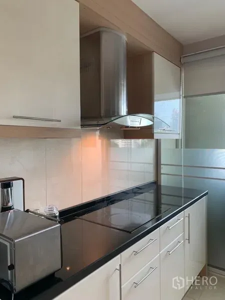 公寓 出租在Khlong Toei, Bangkok - 现代封闭式一字型厨房，黑色石材台面，电磁炉与不锈钢抽油烟机，磨砂玻璃门。