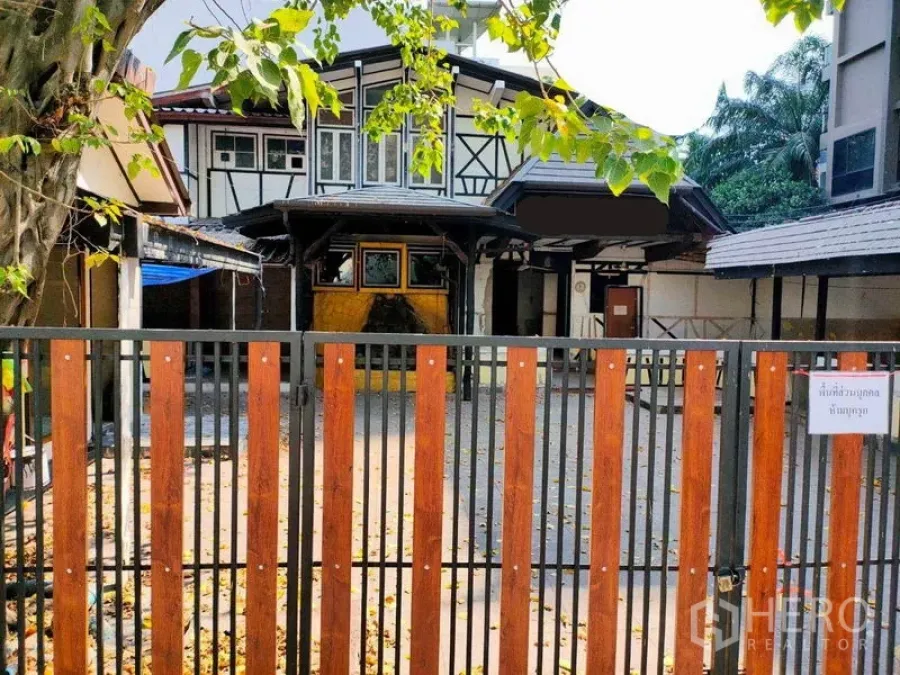 零售空间 出租在Khlong Toei, Bangkok - 都铎风格商铺外立面，木金属围栏与宽阔前院，设有遮雨门廊，位于城市街区。