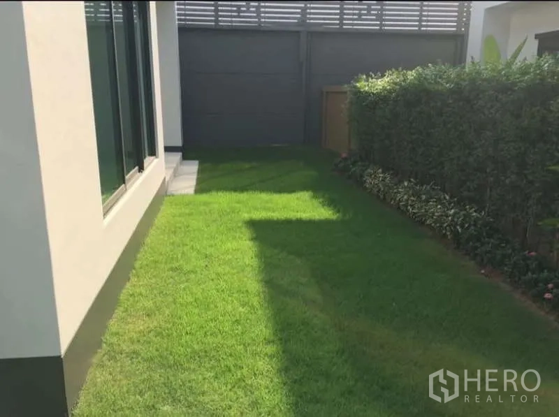 บ้าน ให้เช่าในBang Kapi, Bangkok - สนามหญ้าส่วนตัวข้างบ้านมีแนวพุ่มไม้ และประตูรั้วสีเข้ม