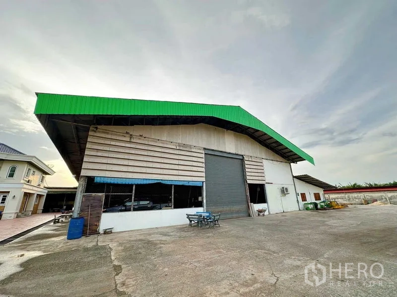 Warehouse for rent in Sai Noi, Nonthaburi - Front view of warehouse with high gable roof, big roller door and open parking apron.