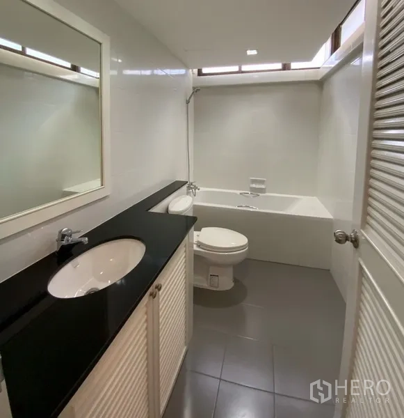 公寓 出租或出售在Watthana, Bangkok - 浴室设浴缸、淋浴、坐便器及长形黑色台面洗手台。