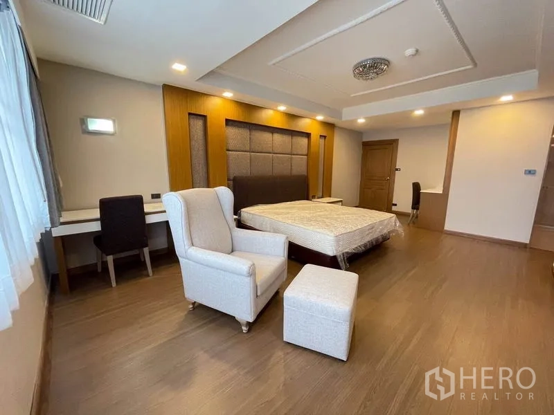 Condominium for rent in Watthana, Bangkok - Bedroom corner with armchair and ottoman, study desk, and soft lighting.