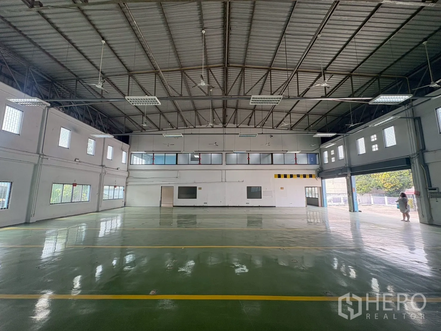 คลังสินค้า for rent in Phra Khanong, Bangkok - ฮอลล์อุตสาหกรรมสว่าง โครงหลังคาเหล็ก หน้าต่างบล็อกแก้ว และพื้นสีเขียวมันวาว.