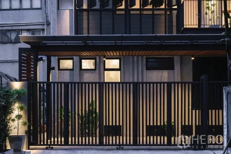 ทาวน์เฮาส์ ให้เช่าในKhlong Toei, Bangkok - ภาพด้านหน้าพร้อมรั้วระแนงสีดำ ระเบียงมีบานเกล็ด และสวนหย่อม
