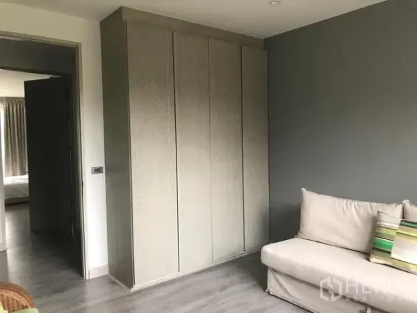 Townhouse for rent in Khlong Toei, Bangkok - Room with built-in wardrobe, gray accent wall and compact sofa.