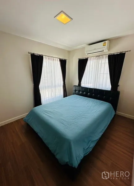 Detached House for sale in Prawet, Bangkok - Cozy bedroom with double bed, AC and corner windows with curtains.