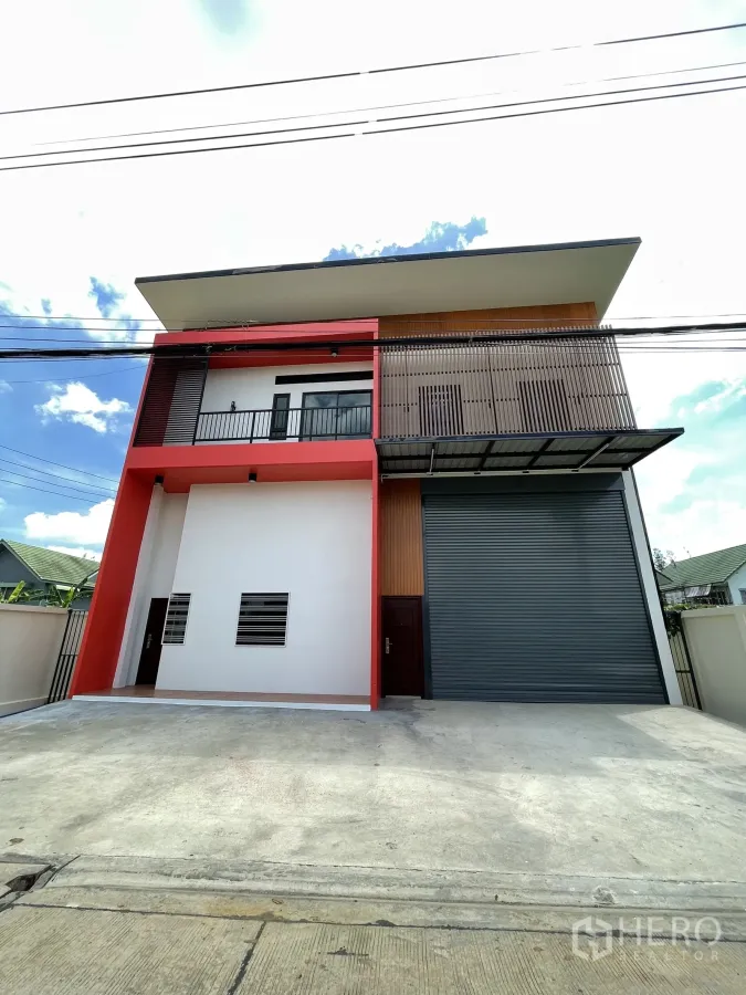 โรงงาน ให้เช่าหรือขายในLam Luk Ka, Pathum Thani - ด้านหน้าโรงงานสองชั้น โทนแดงพร้อมระเบียงและประตูม้วนสีเทาบานใหญ่