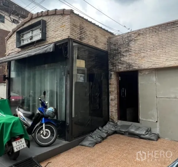 พื้นที่ขายปลีก ให้เช่าในWatthana, Bangkok - มุมโชว์เคสกระจกและทางเข้าอาคารอิฐ มีกันสาดและโครงป้าย