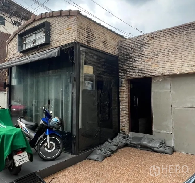 พื้นที่ขายปลีก ให้เช่าในWatthana, Bangkok - มุมโชว์เคสกระจกและทางเข้าอาคารอิฐ มีกันสาดและโครงป้าย