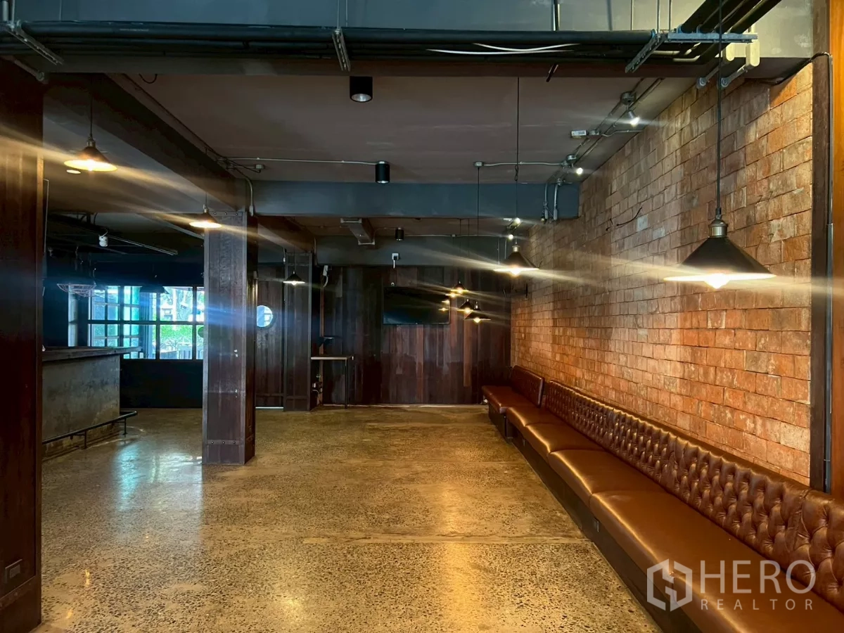 零售空间 出租 - 大开间内有砖墙、长椅、顶灯与木质细节。