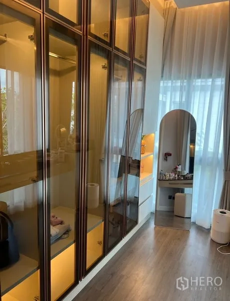 Detached House for sale in Bang Kapi, Bangkok - Walk-in wardrobe with glass-front cabinets, vanity and tall sheer curtains.