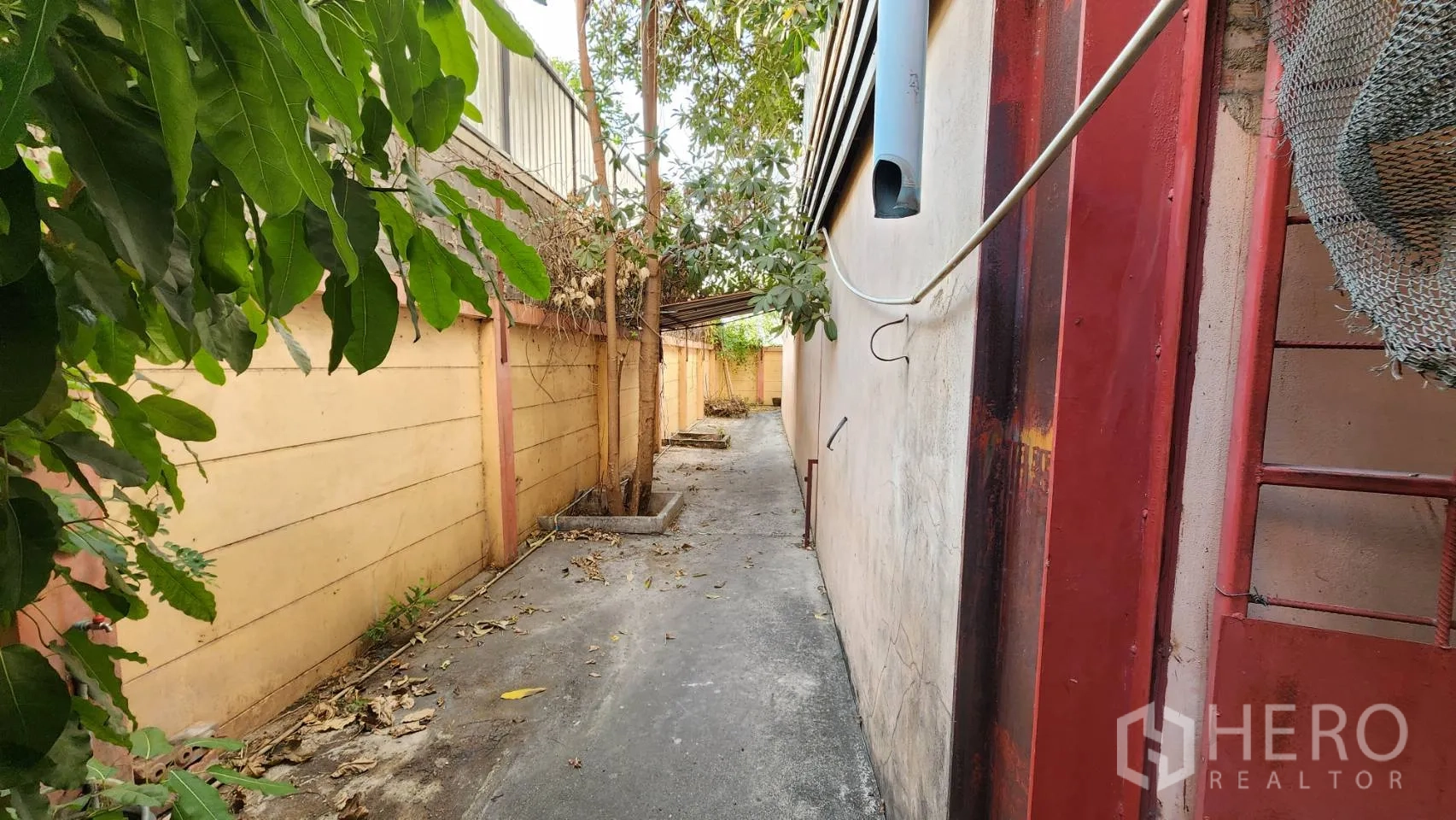 货栈 出租在Nonthaburi - 仓库后方有树荫的小巷与围墙。