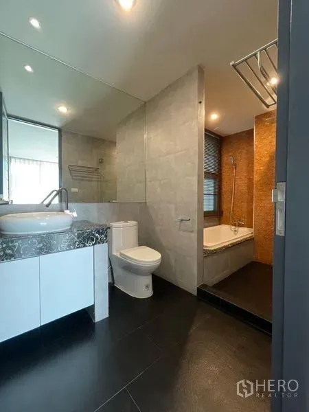 Condominium for rent in Watthana, Bangkok - Modern bathroom with vessel sink vanity, toilet, bathtub and glass-partitioned shower in gray tiles.