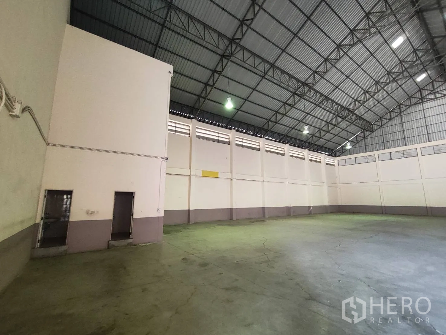 Factory for rent in Krathum Baen, Samut Sakhon - Warehouse corner with tall walls, ceiling lights, and a metal sheet roof structure.