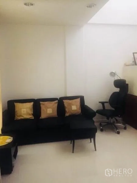 ทาวน์เฮาส์ ให้เช่าในBang Kapi, Bangkok - มุมนั่งเล่นกะทัดรัด โซฟาสีดำ หมอนอิง และเก้าอี้ทำงาน