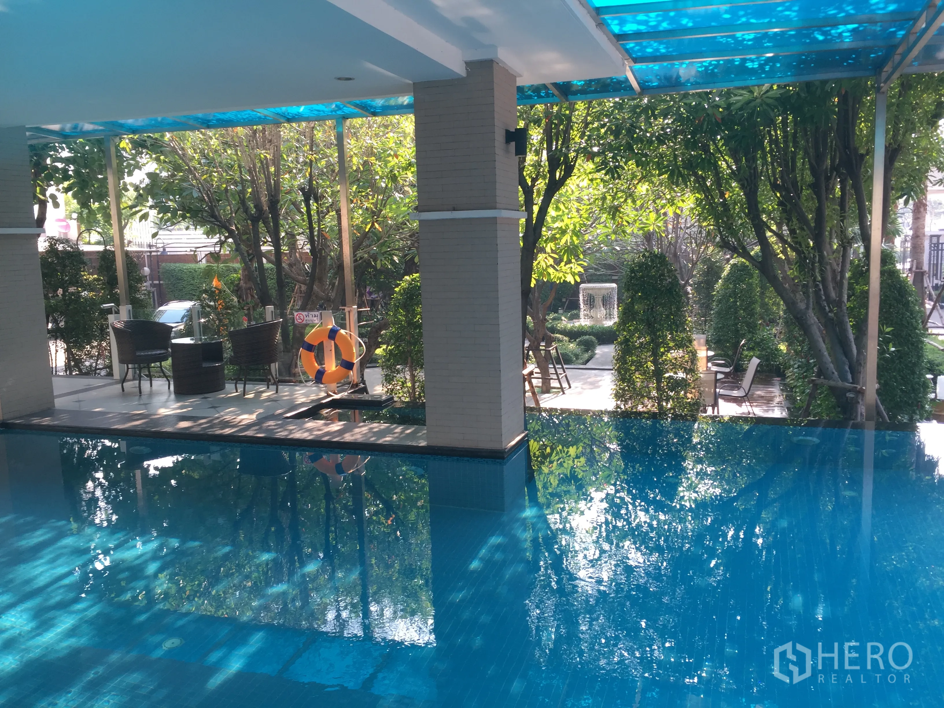 Townhouse for rent in Bang Kho Laem, Bangkok - Covered communal swimming pool with garden seating and mature trees.