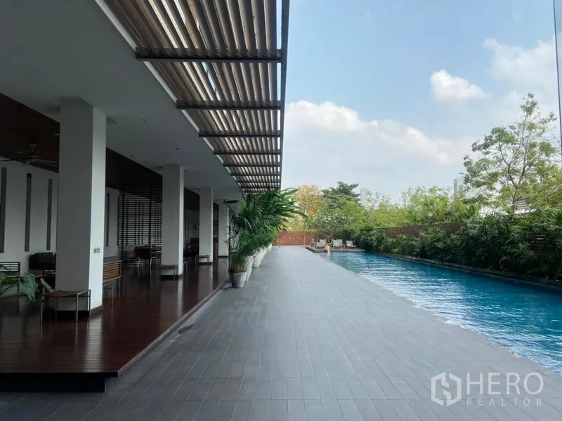 Condominium for rent in Yan Nawa, Bangkok - Condominium outdoor swimming pool beside shaded deck and greenery.