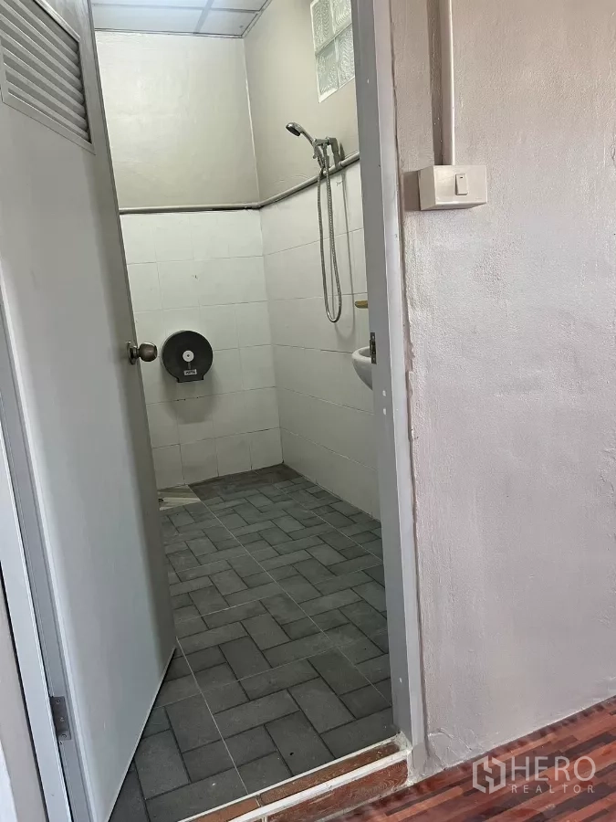 Warehouse for rent in Lat Lum Kaeo, Pathum Thani - Tiled restroom with handheld shower, sink, and gray floor tiles.