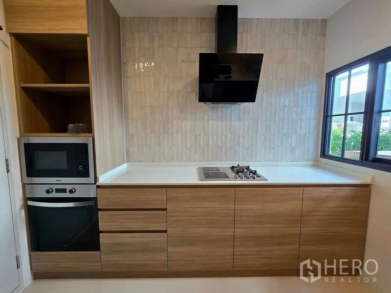 Detached House for rent in Bang Phli, Samut Prakan - Thai kitchen with gas cooktop, range hood and built-in oven by window.