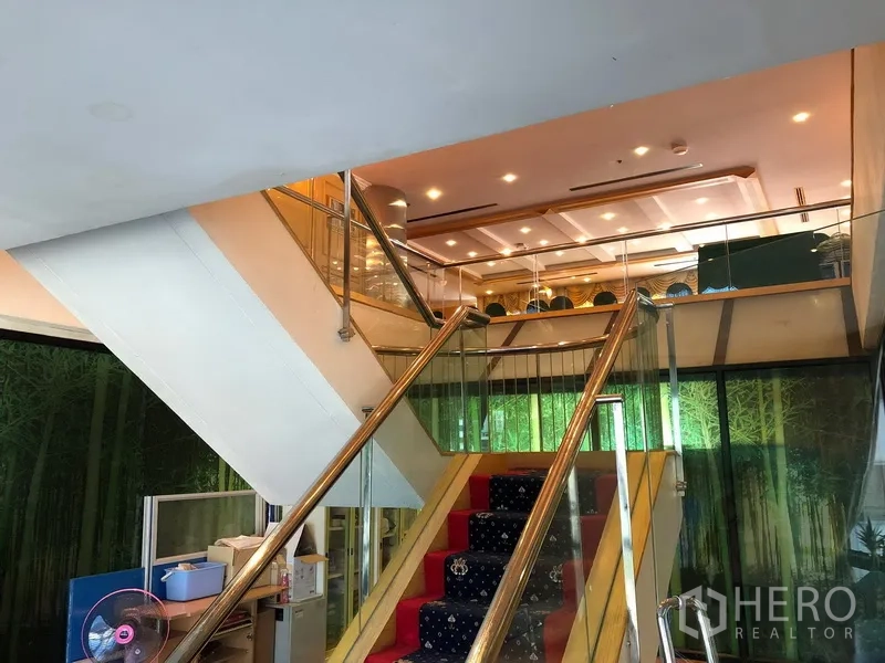 Office Space for rent in Bang Na, Bangkok - Glass-railed internal staircase leading to a mezzanine level with spotlit ceiling.