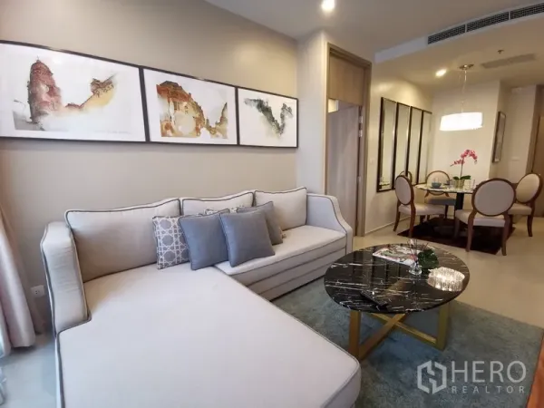 คอนโด ให้เช่าในPathum Wan, Bangkok - โซนรับแขกและทานอาหารแบบเปิดโล่ง โซฟาเข้ามุมสีครีม โต๊ะกลางหินอ่อน และโต๊ะกลมใต้โคมระย้า